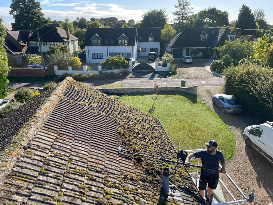 Manual roof tile moss scraping from an access tower